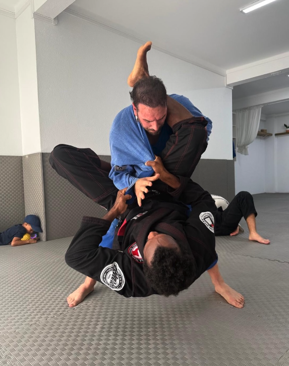 Adultos em rolling durante treino de BJJ